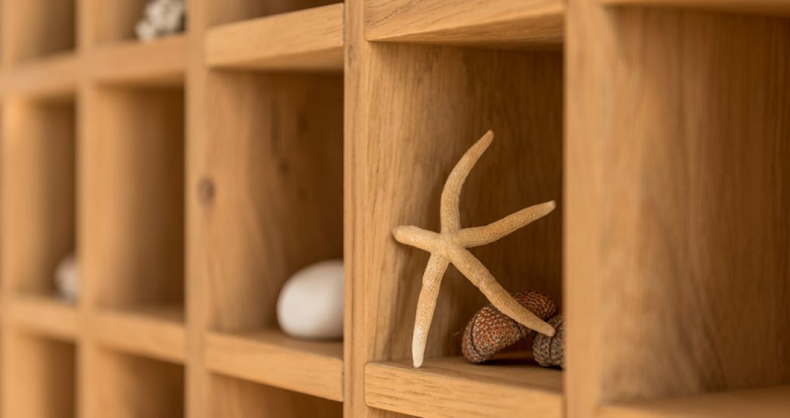 Detail of a wooden grid shelving unit decorated with a starfish, sea urchins, and smooth white stones.