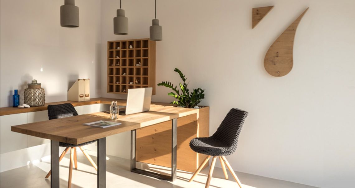 Bright and modern workspace featuring a wooden desk, black woven chairs, and hanging concrete lights, illuminated by natural sunlight.